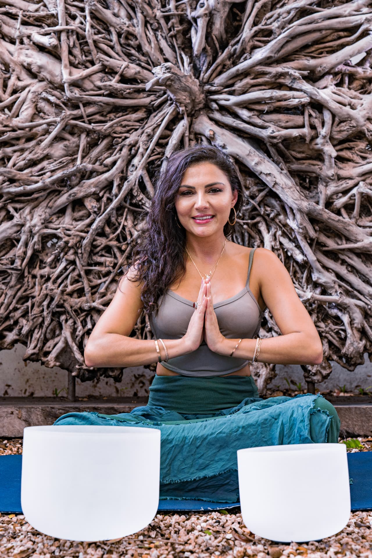 Elmira seated in front of her crystal singing bowls, hands at heart