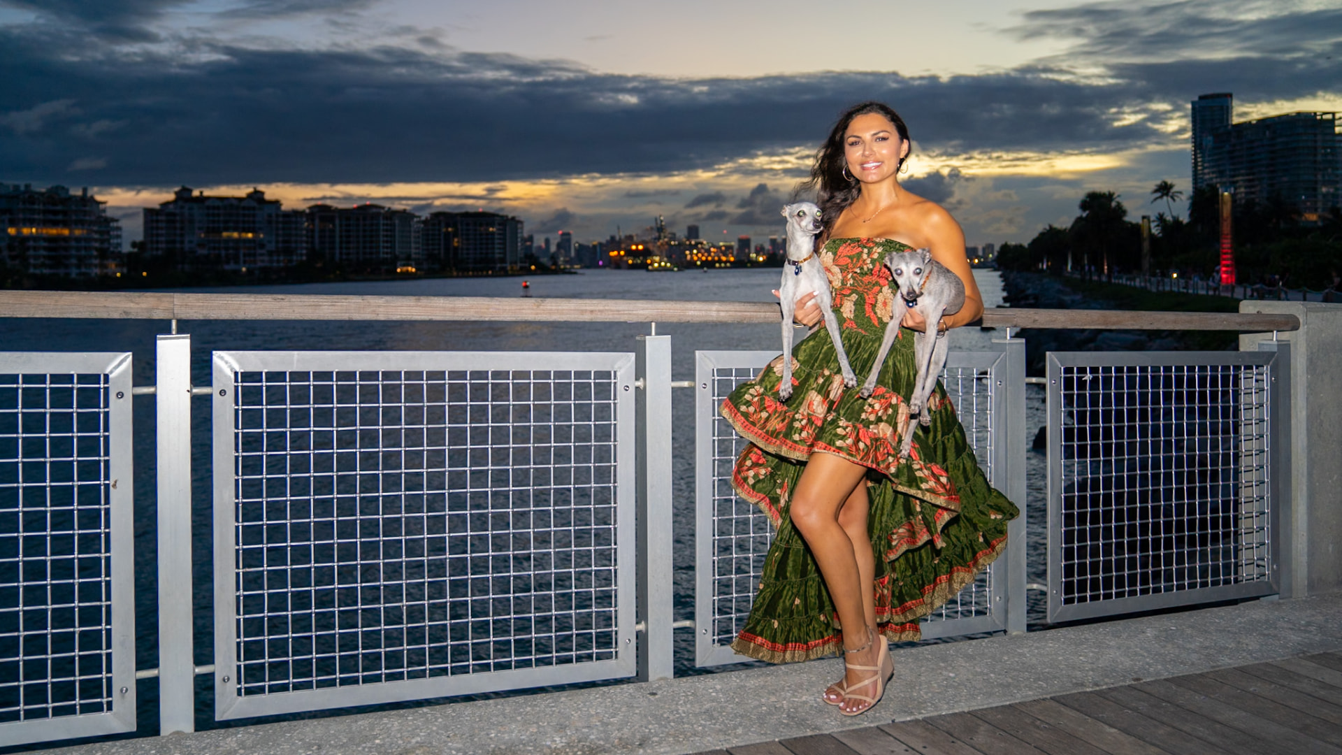 Elmira and her greyhounds at the railing overlooking the water at sunset